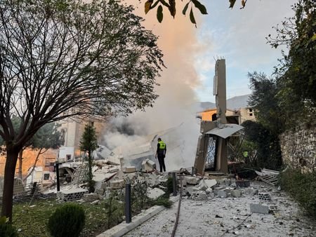 A civil defence member stands on rubble at a damaged