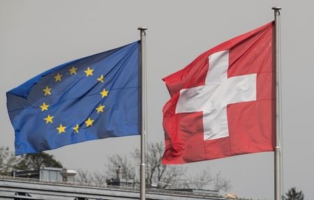 Switzerland's national flag flies beside the one of the European