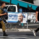 A soldier walks past election campaign banners depicting former Israeli