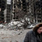 Nurse Svetlana Savchenko stands next to the destroyed building where