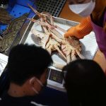 A shopkeeper shows a king crab imported from Russia to