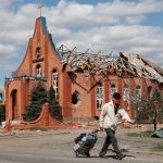 A local resident walks past a heavily damaged church in