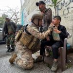 A Lebanese army soldier assists a boy, affected by tear
