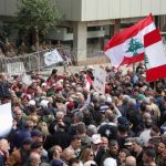 Demonstrators hold Lebanese flags as they gather during a protest