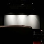 The projection screen is seen inside a cinema hall before