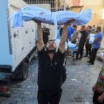 A Palestinian man from al-Badrasawi family carries the body of
