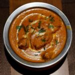 A freshly prepared butter chicken dish is placed on a