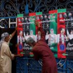 Workers hang campaign posters of a political party, ahead of