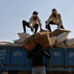 Laborers unload sacks filled with wheat at a wholesale grain