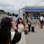 Tourists take photos of Mount Fuji appearing over a convenience