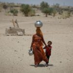 A woman walks back towards her home after filling water