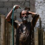 A man cools off with a water hose during a