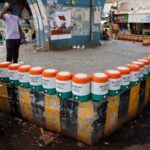 People drink water from water jars installed under a flyover