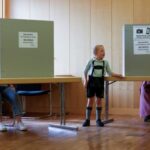 Residents in traditional dress vote during the European Parliament election