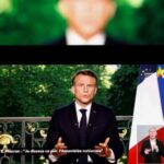 French President Emmanuel Macron appears on a screen as he