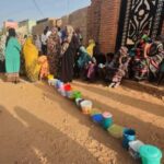 FILE PHOTO: Residents collect food in containers in Omdurman