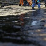 Workers clean up the oil slick at Tanjong Beach in