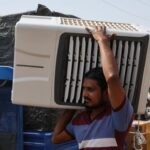 A worker carries an air cooler for delivery to a