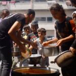 Palestinians gather to receive food cooked by a charity kitchen,