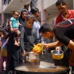 Palestinians gather to receive food cooked by a charity kitchen,