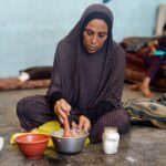 A displaced Palestinian woman prepares food at a school classroom