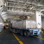 Lorry transporting aid loads onto a U.S. cargo vessel for