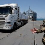 Trucks carry humanitarian aid across Trident Pier