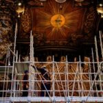 Workers mount scaffolding around a baroque sculpted bronze canopy by