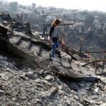 Ingrid Crespo walks on the remains of her house burned,