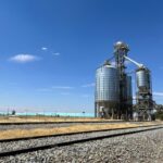 A grain elevator stands next to piles of stored grain