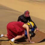 Dune 7 sandboarding instructor Devon Waters shows a tourist how
