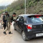 Indian police officers stop a vehicle at a check point