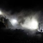 Rescuers work at the site of an apartment building hit