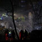 Rescuers work at the site of an apartment building hit