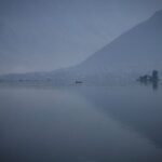 Kashmiri men row a traditional shikara boat on the waters