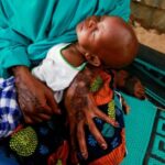 FILE PHOTO: A mother carries her sleeping baby during a