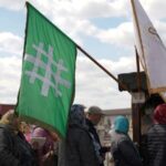 People queue up at a tomb bearing the flag with