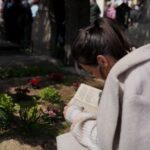 People queue up at a tomb bearing the flag with