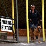 A woman and her dog leave a polling station in