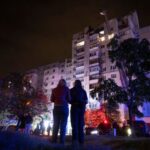 People look at an apartment building that was damaged in
