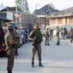 Indian security force personnel stand guard near the site of