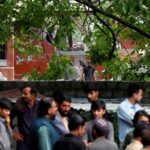 People gather next to a damaged portion of Bilal Mosque