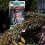 Man walks past a poster of the Chief of Army