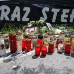 Flowers and candles are seen in front of the fences