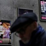 FILE PHOTO: A tube passenger walks past a sign advertising