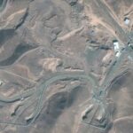 A satellite image shows trucks and bulldozers near the entrance