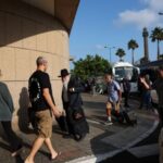 Foreign nationals walk to board a bus to be evacuated
