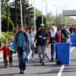 FILE PHOTO: Migrants pass by garbage bins as they walk