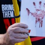 Protestors stand at the entrance to Kibbutz Nir Oz, on
