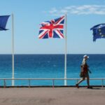 A woman walks past British, French and EU flags on